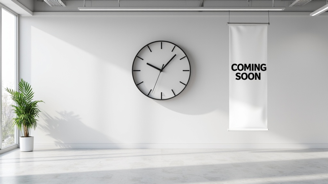 Medium shot of a minimalist office space with a large wall clock showing 11:59 and a lone "Coming Soon" banner hanging nearby, creating an atmosphere of anticipation for an imminent product launch